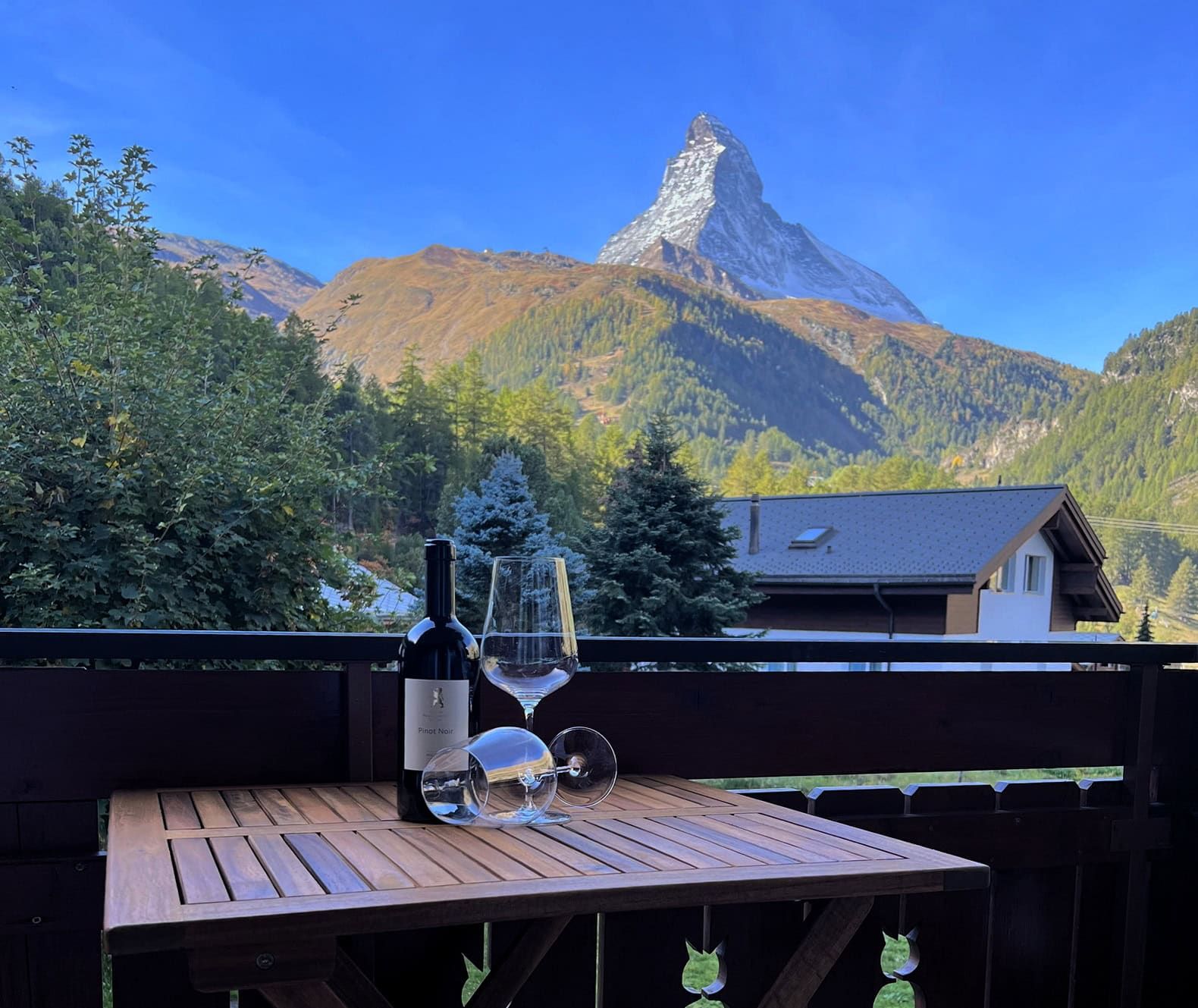 Balkontisch mit Weinflasche und Glas vor dem Matterhorn