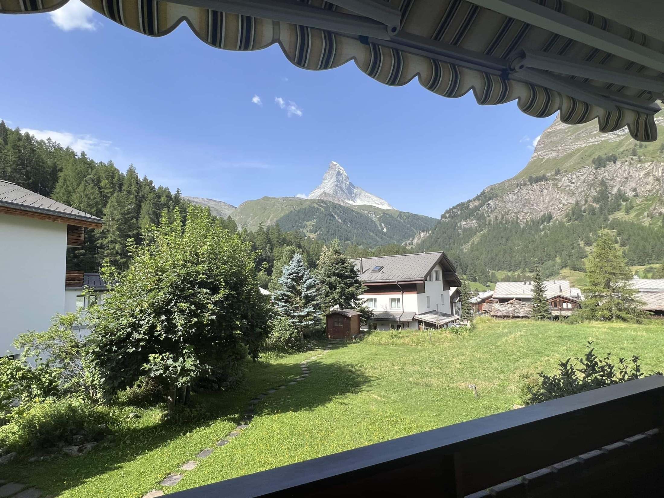 Das Matterhorn über einer Wiese und Chalets, gesehen unter einer Balkonmarkise